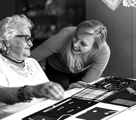 A volunteer sitting with a patient at a table at home